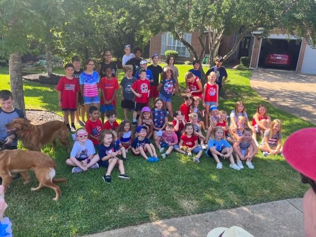 Group photo of Rustic Woods children in red, white, and blue on a front lawn