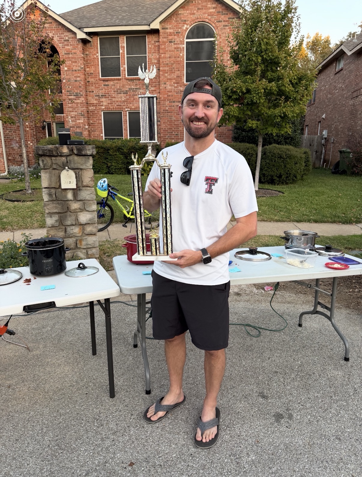 The chili cook-off winner holding trophies beside the tasting tables in Rustic Woods