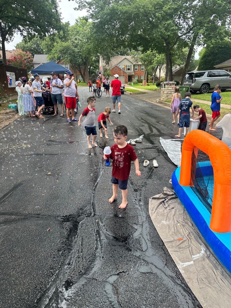 Children playing in the street with water toys during Fourth of July celebrations